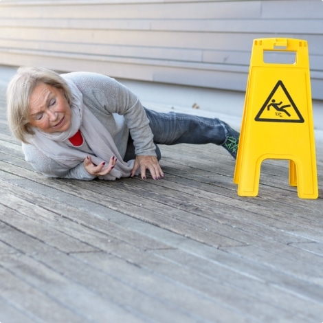 elderly woman on floor next to wet floor sign after slip and fall accident (image possibly on wrong page- doesn’t seem motorcycle related)