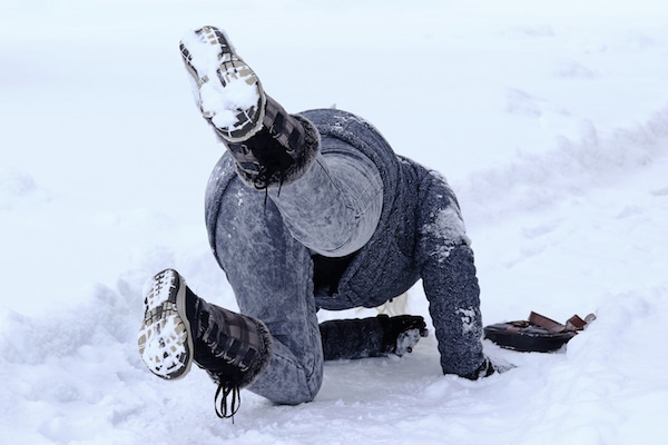 person slips and falls on a snowy walkway