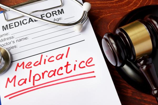 medical malpractice written in red ink on a medical form with a judg'es gavel next to the form