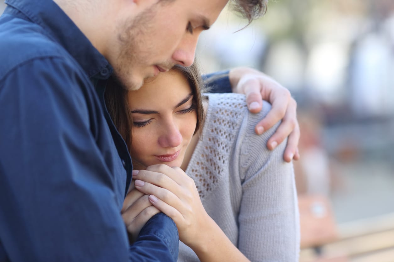 A man embracing a sad woman.