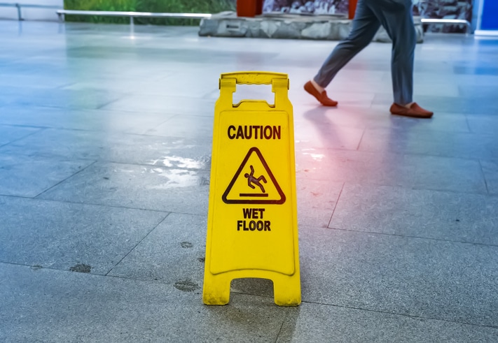 A picture of a wet floor sign next to a puddle of water.