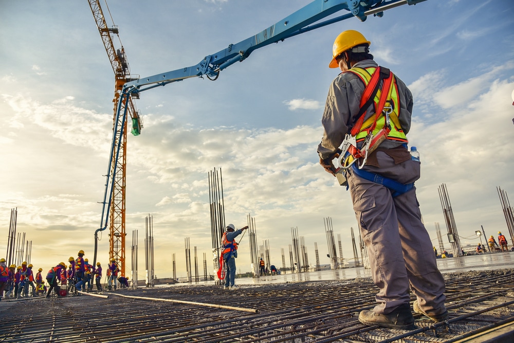 A worker in safety gear watches from afar a crane project happening outside