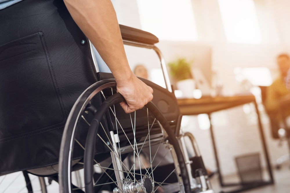 A close up of a man rolling the wheel on his wheel chair