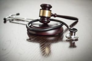 Gavel and Stethoscope on Reflective Wooden Table.