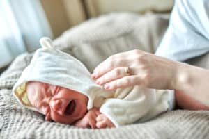 Newborn crying baby in white clothing
