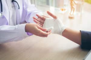 Traumatologist is taking care of the patient, woman doctor bandaging a hand.