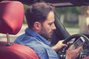 Man using cell phone texting while driving