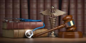 A gavel, stethoscope, books, and caduceus sign on a table