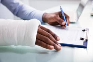A man in a cast filling out an SSDI claim form