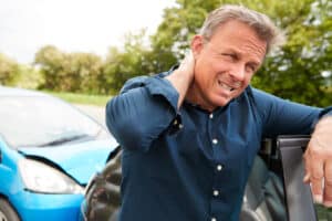 A man holding his neck after getting whiplash from a car accident