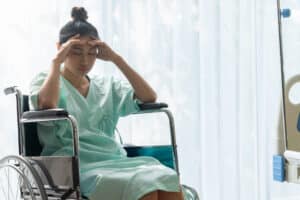 Woman in wheelchair holding her head in stress after experiencing medical malpractice