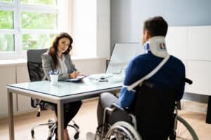 Injured man in wheelchair and neck brace meeting with attorney to discuss SSDI claims