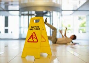 Caution: Wet Floor sign with a person falling on the floor in the background.