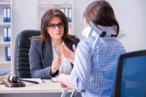 Woman in neck brace and crutches speaking to an attorney for help applying for SSDI benefits.