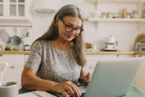 Older woman on SSDI using a laptop at home to research part-time work options