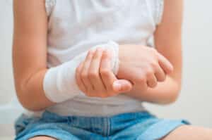 Child holding her wrist which is wrapped up after being injured at school