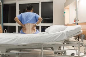 Man sitting in hospital bed wearing back brace after sustaining a spinal cord injury