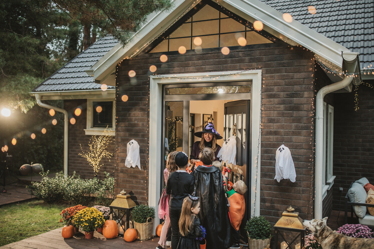 Policeman going over car accident scene Children in Halloween costumes visit a decorated home, highlighting property safety and premises liability risks for holiday visitors.